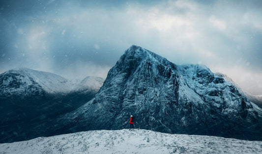 Person standing alone in front of a snow-covered mountain — the longevity journey from foundation to frontier